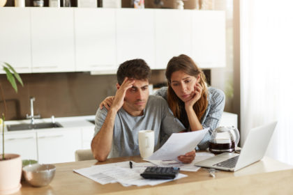 Unhappy couple managing home accounts in kitchen, trying to save some money by cutting family expenses. Finances, bankruptcy, taxes, money, accounting and financial problems concept